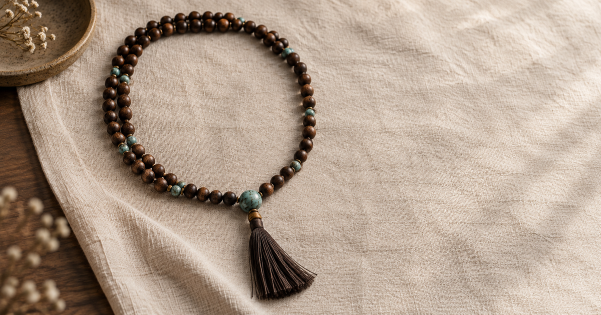 Mala beads arranged on warm neutral fabric with a distinct terminal bead
